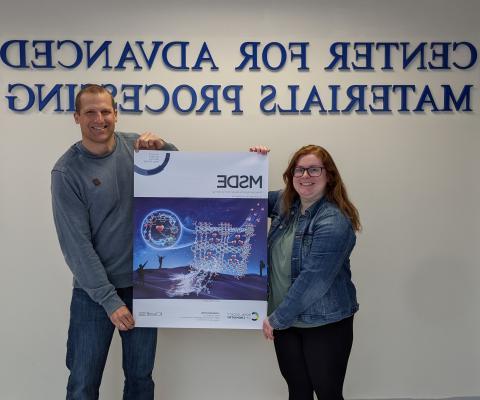 Charlene C. VanLeuven and Mario Wriedt hold an enlarged cover of MSDE Journal